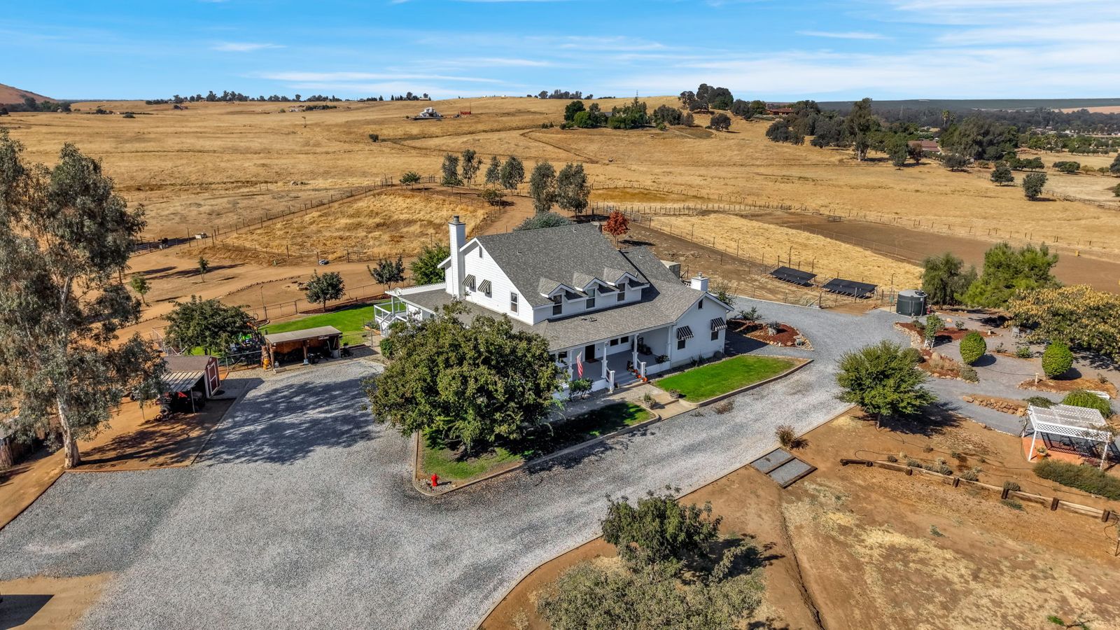 Aerial view of the white farmhouse at 1969 N Pederson Ave on its acreage in the Sanger foothills